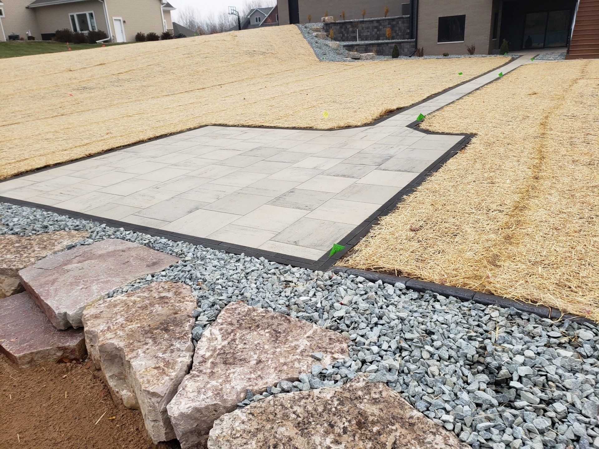 Stone patio and pathway with gravel and a retaining wall.