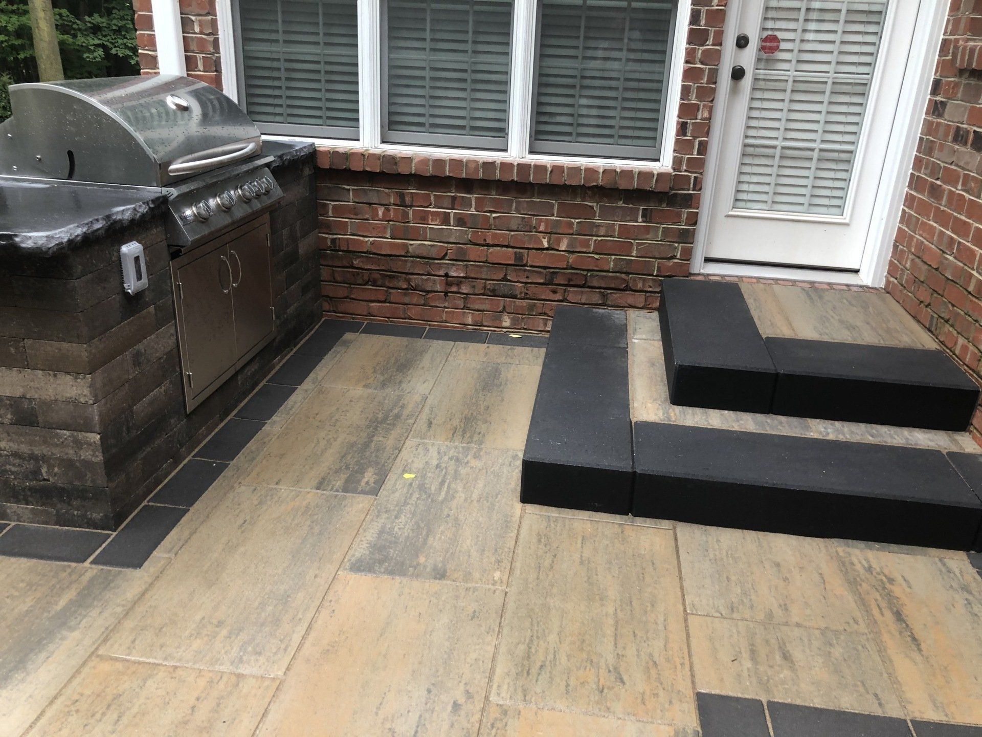 Outdoor patio with grill and steps made of brick and stone.