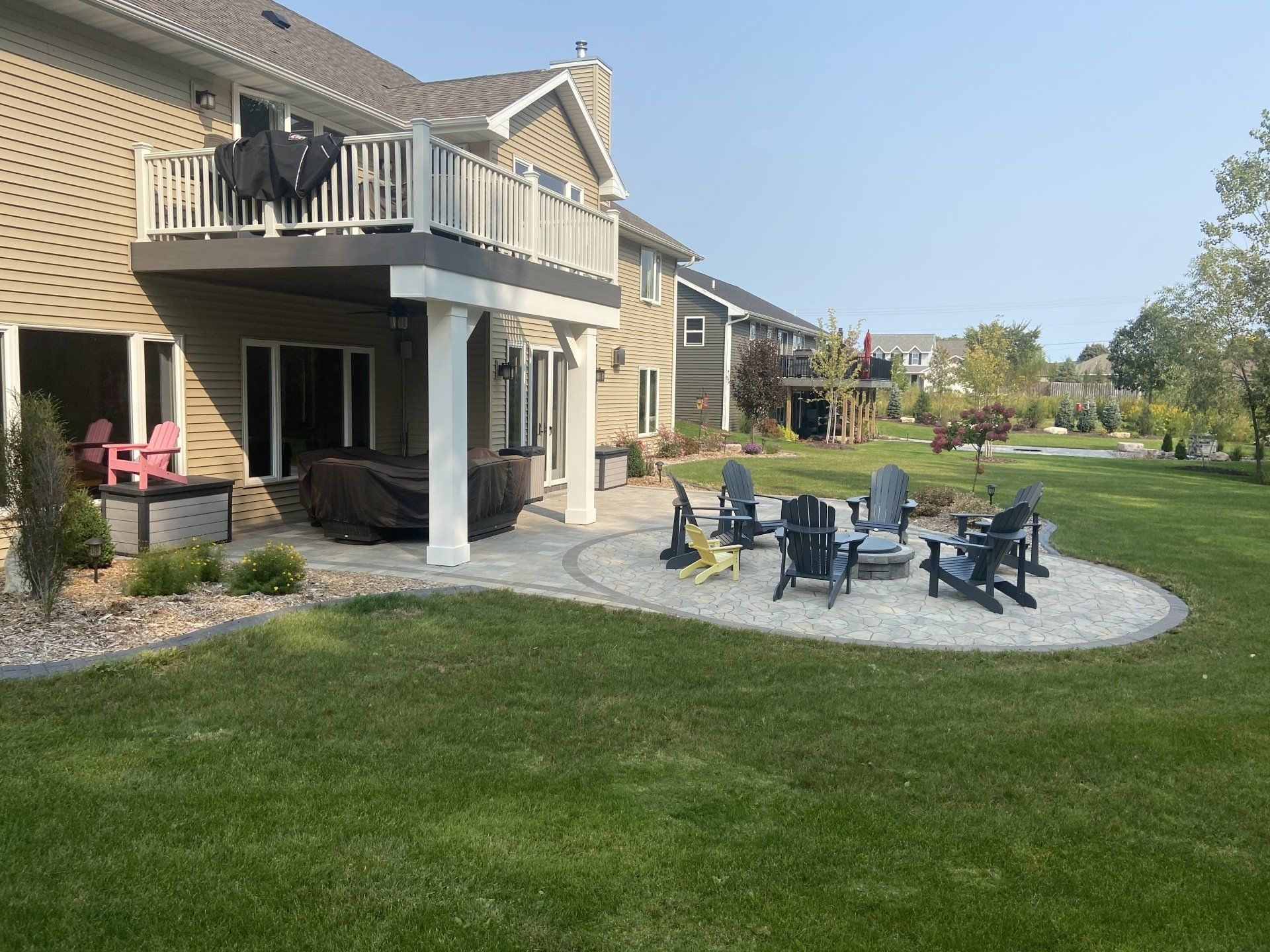 Backyard with patio, fire pit, lawn, and multi-level house with a deck.