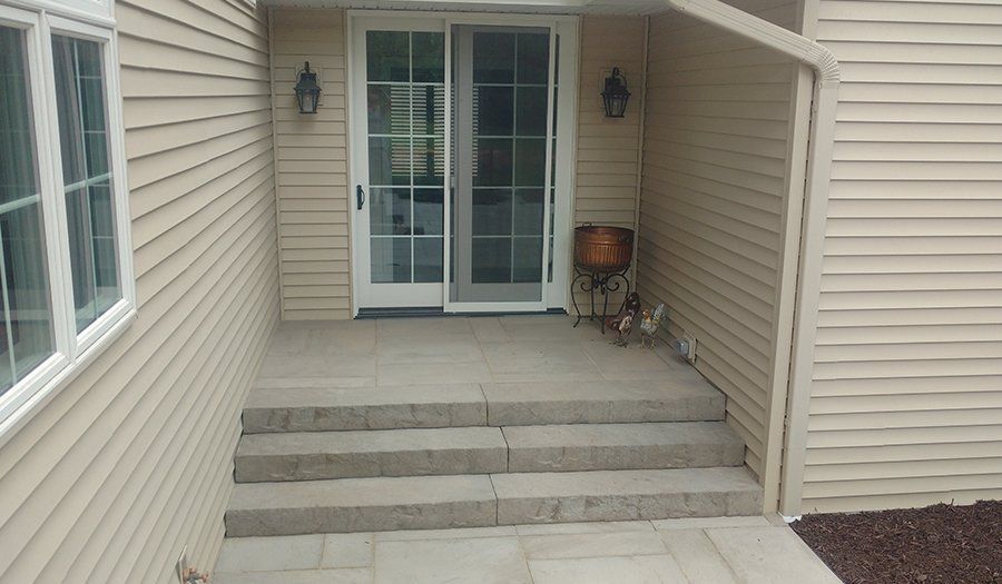 Exterior entrance with steps leading to a sliding glass door; beige siding, stone steps.
