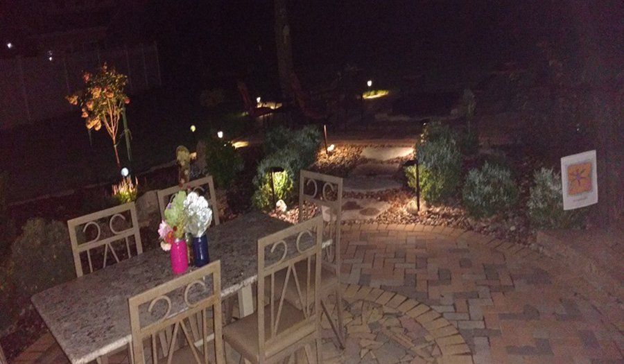 Patio with outdoor furniture, lit pathway, and decorative lights at night.