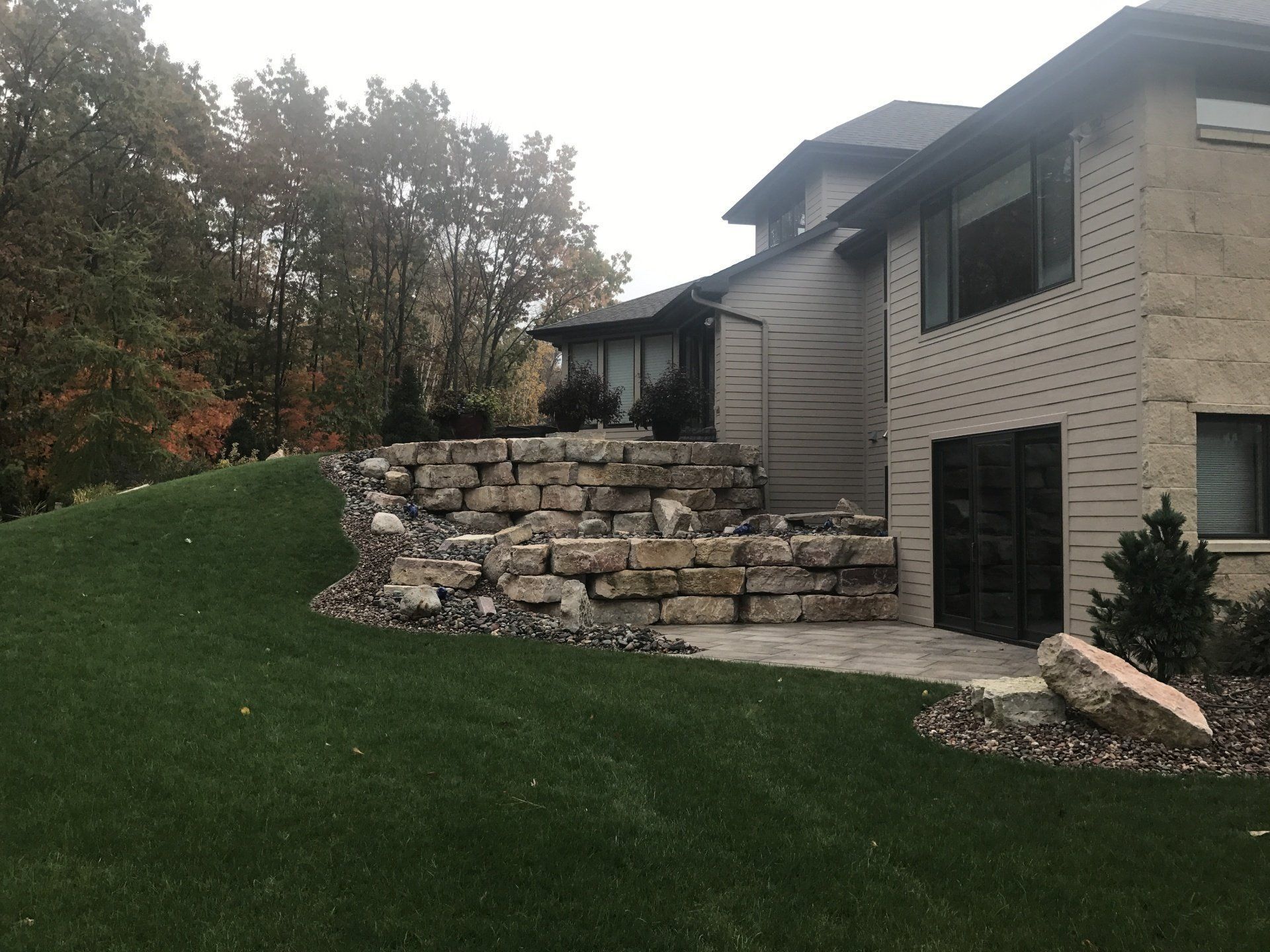 House exterior with a stone retaining wall and a green lawn.