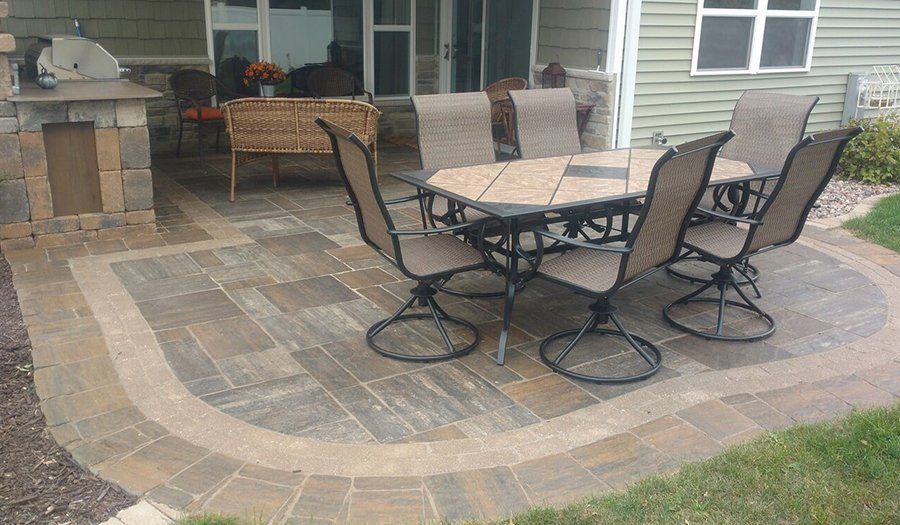 Patio with a table and chairs, bordered by brickwork, with a stone structure to the left.
