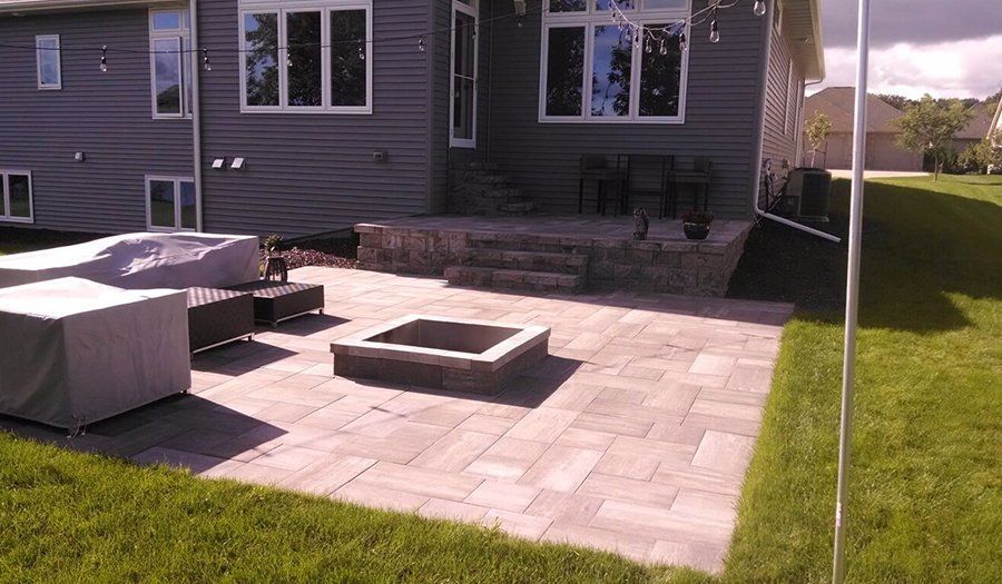 Backyard patio with fire pit, seating, and steps leading to house entrance.