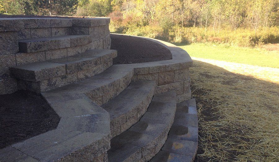 Stone retaining wall with steps leading up to grassy area, outdoors.