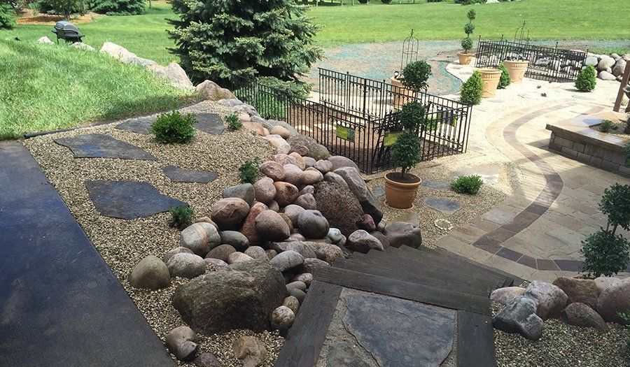 Landscaped backyard with rock garden, stepping stones, and decorative paved areas.
