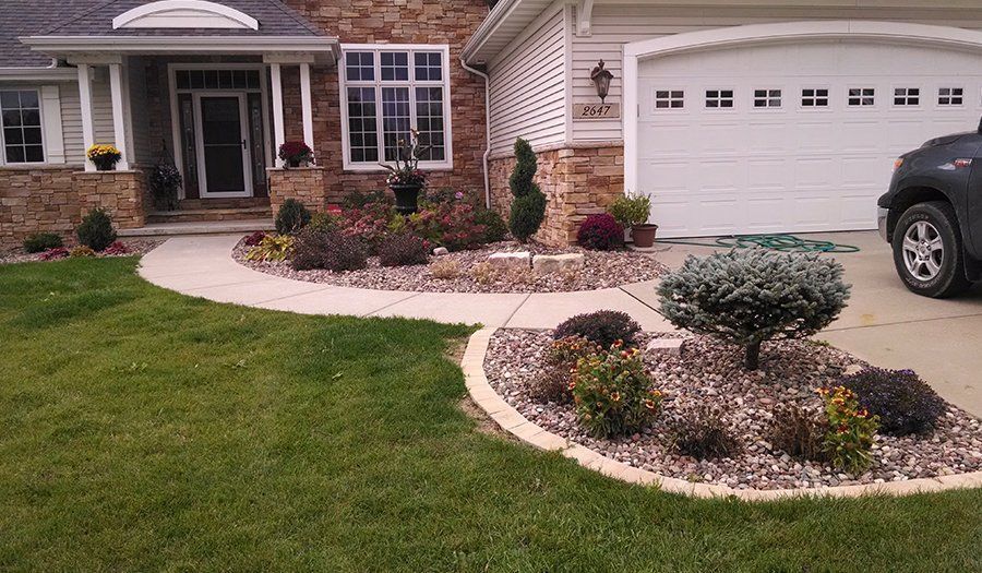 House exterior with landscaped front yard, stone accents, and curved concrete walkway.