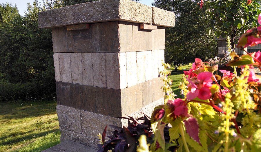 Stone block beehive with a colorful flower garden in the foreground.