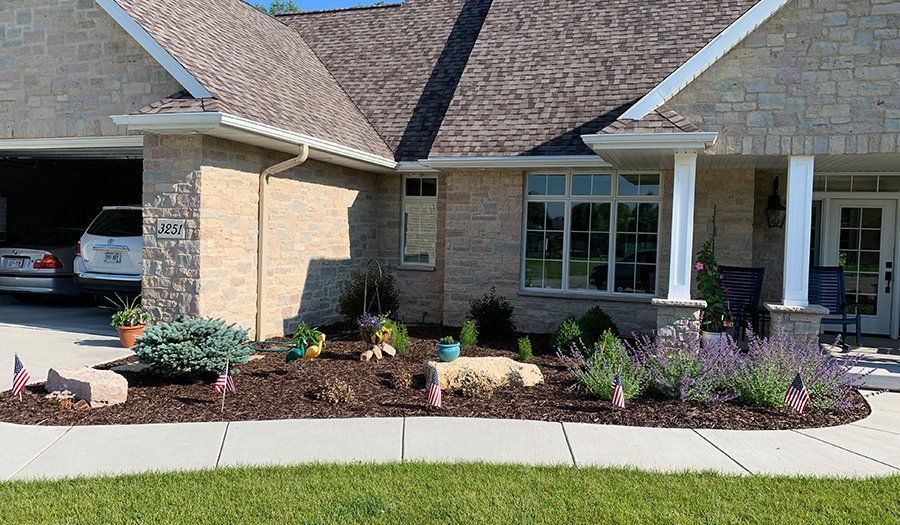 House with stone facade, landscaped yard, garage, and a car visible.