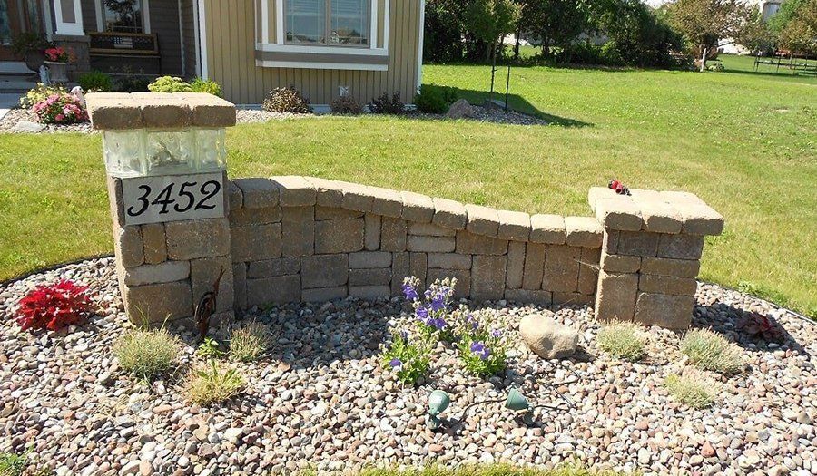 Stone mailbox with house numbers 3452, small retaining wall, flowerbed in front.
