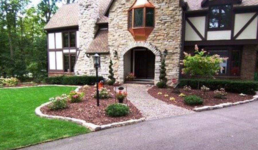 Stone house with landscaped yard, pathway, and dark wood trim.