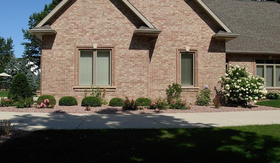 Brick house exterior with small windows, and landscaping.