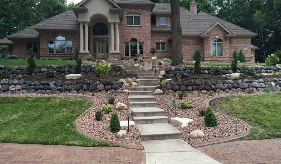 Brick house with stone retaining walls, steps, and landscaping.