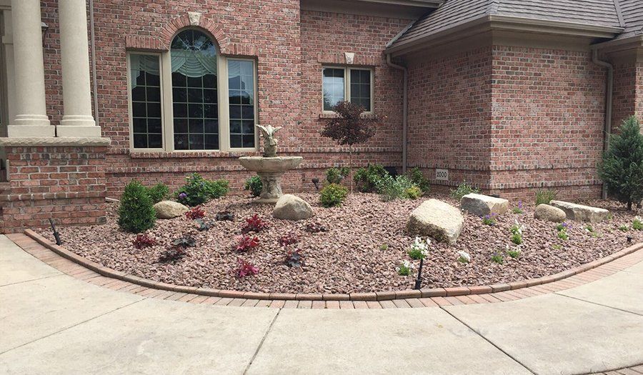 Brick house exterior with a landscaped yard and a decorative fountain.