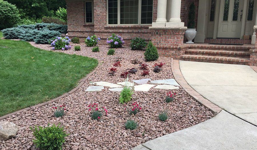 Brick house with a landscaped front yard featuring various plants and red mulch.