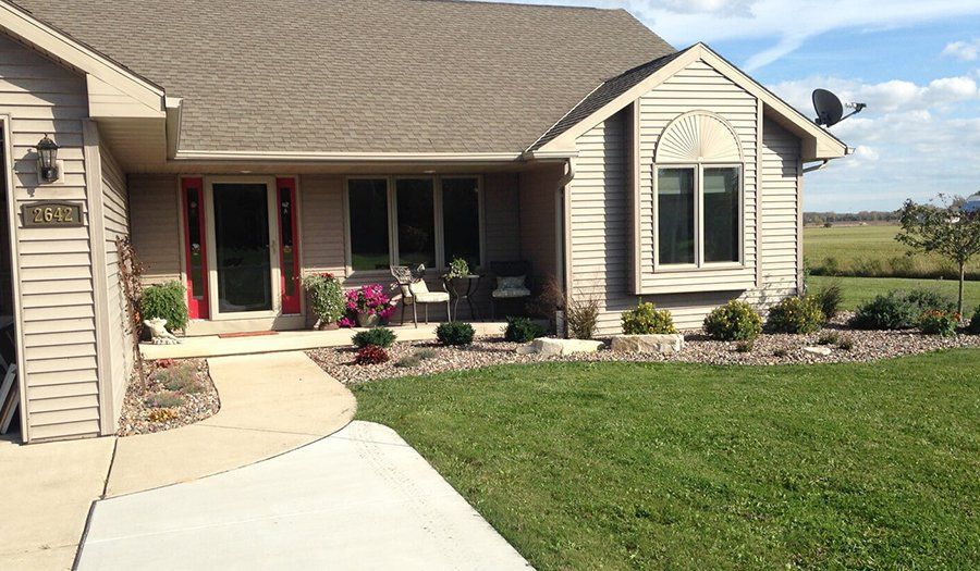 Beige house with a red front door, bay window, and satellite dish against a blue sky.
