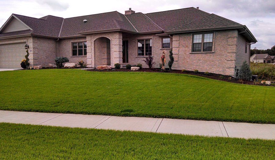 Brick house with a green lawn and a sidewalk in front.