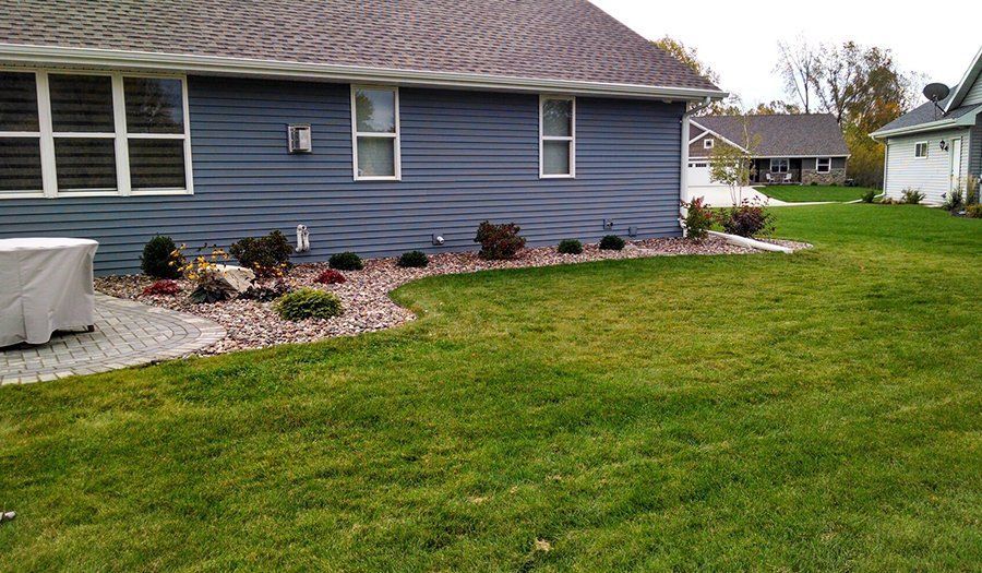 Blue house with landscaped yard and green grass.