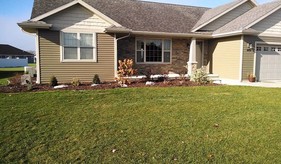 House exterior with brown siding, front lawn, and landscaping.
