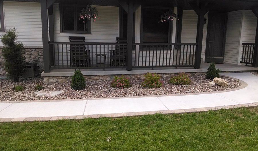 Exterior of a house with a porch and walkway, landscaping with rocks and shrubs.