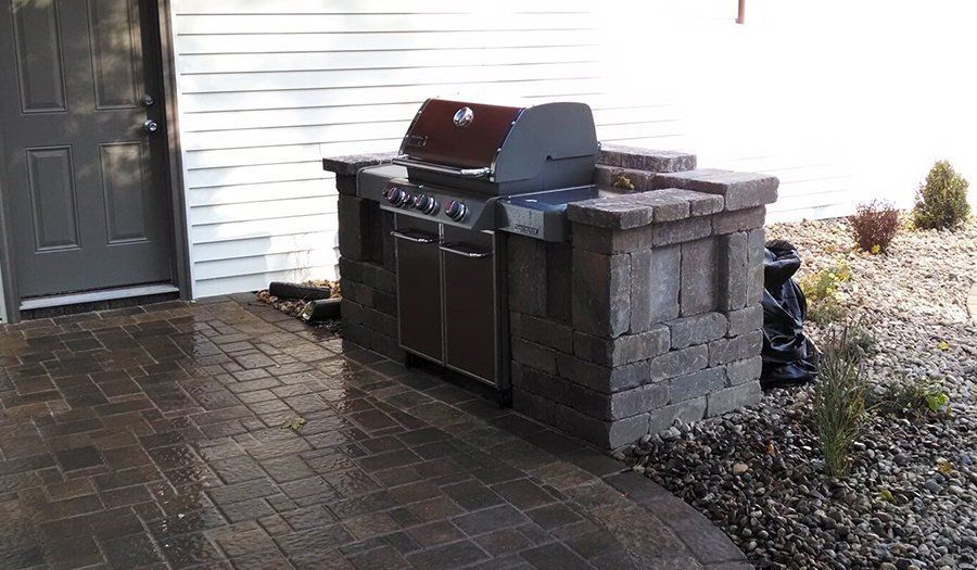 Outdoor grilling station built with stone blocks and brick patio.