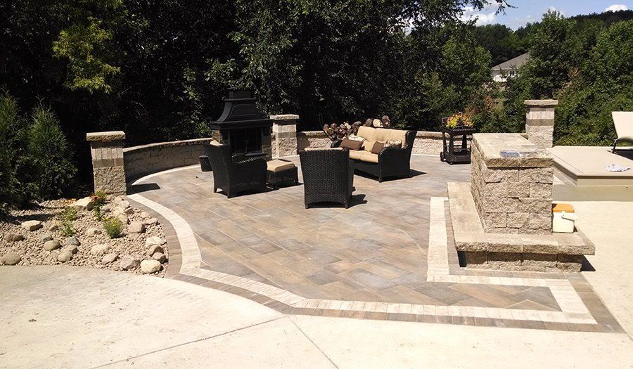 Outdoor patio with stone pavers, seating area, fire pit, and stone columns.
