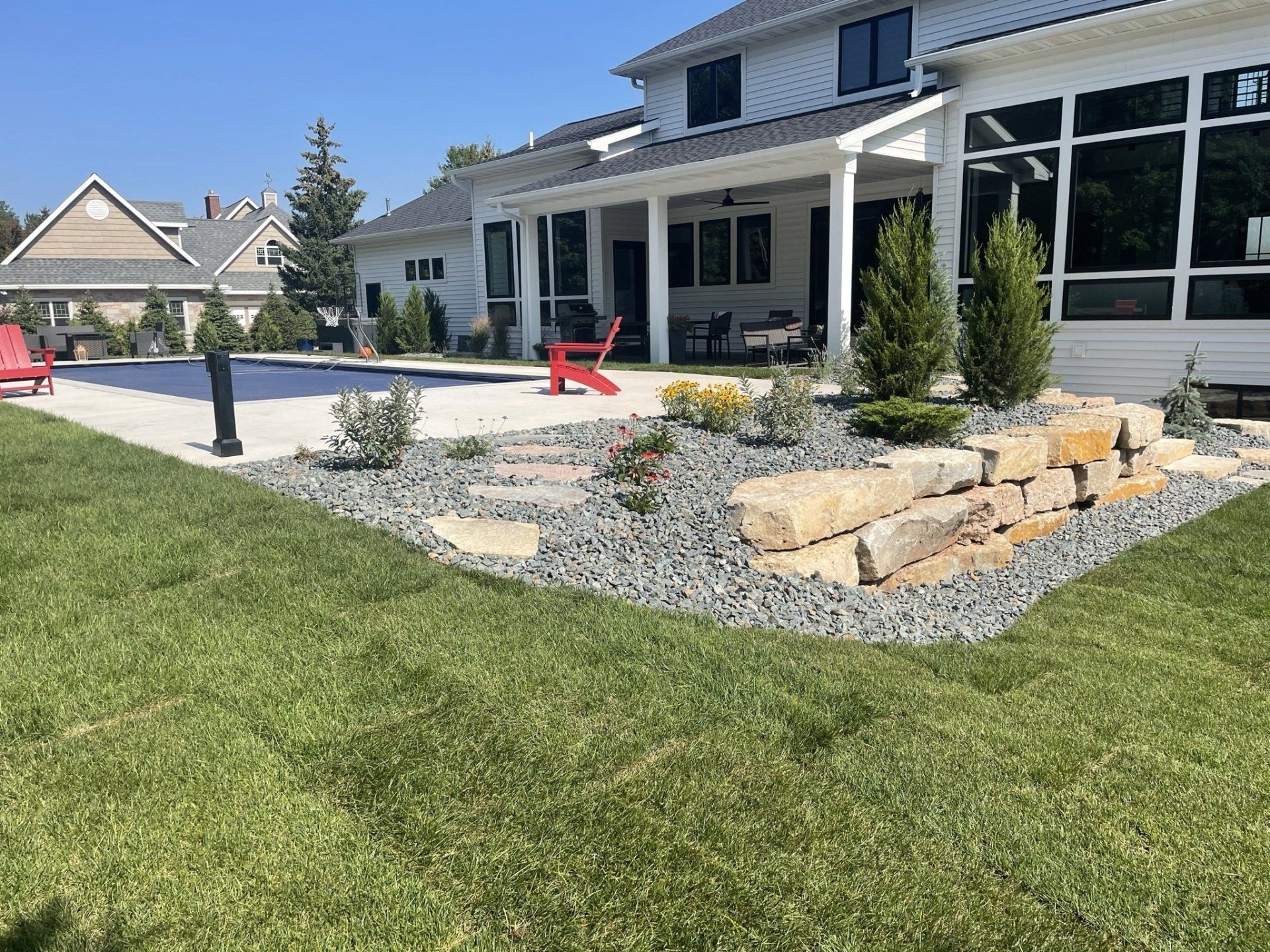 Backyard with stone steps, landscaping, pool, and a white house with a porch.