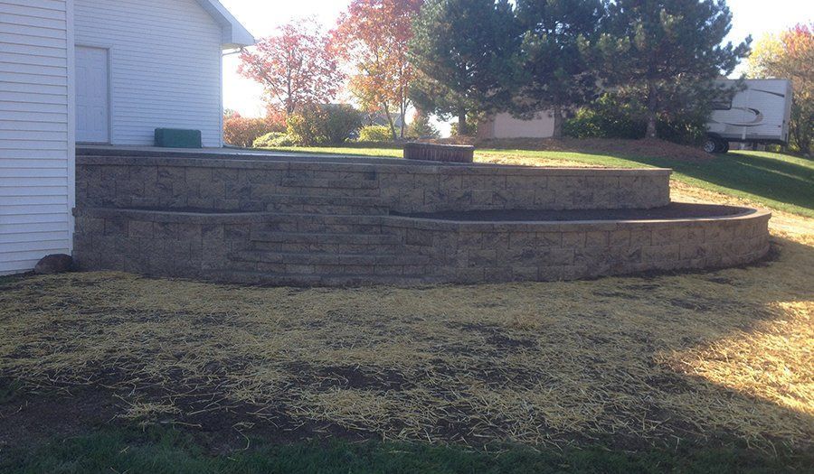 A multi-tiered retaining wall made of blocks in front of a house.