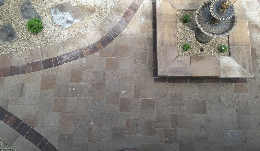 Overhead view of a stone courtyard with a fountain and decorative paving.