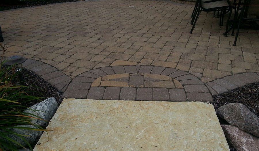 Brick patio with stone entrance and brown and tan pavers.