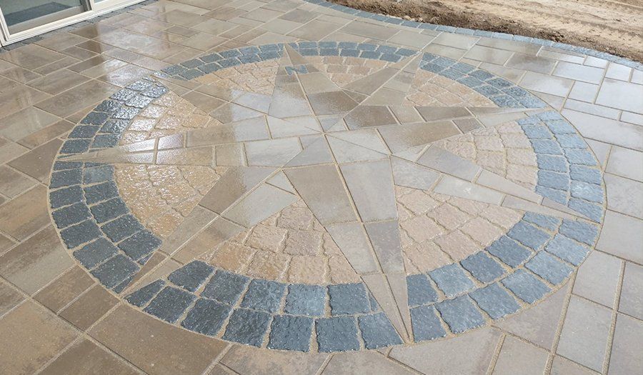 Paver patio with a circular compass rose design in shades of brown and gray.