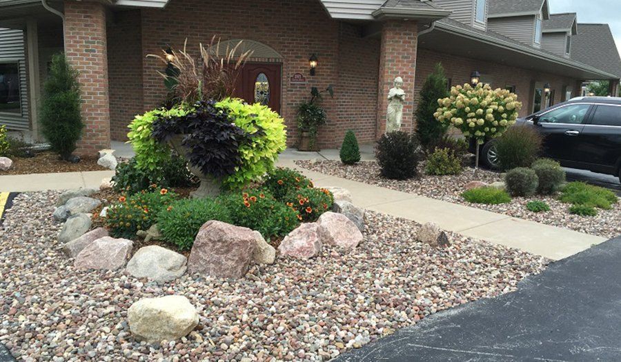 Landscaped entrance with brick columns, plants, and large rocks.