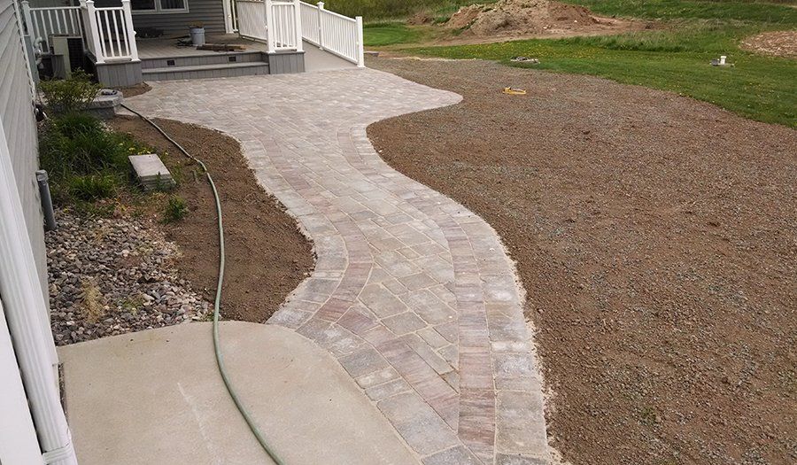 Brick pathway curving through gravel and grass, leading from patio.