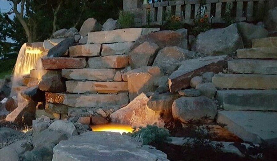 Stone waterfall with cascading water and warm lighting.