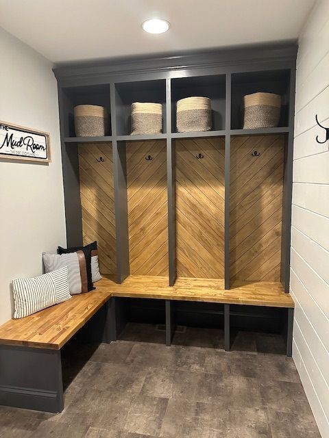 A mud room with a bench , shelves , hooks and baskets.