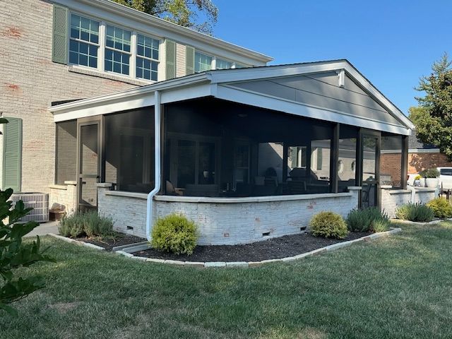 There is a screened in porch in the backyard of a house.