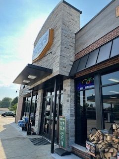 A large building with a lot of windows and a sign on the sidewalk.
