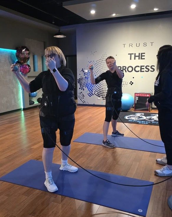 People exercising on yoga mats in a studio with “TRUST THE PROCESS” on the wall.
