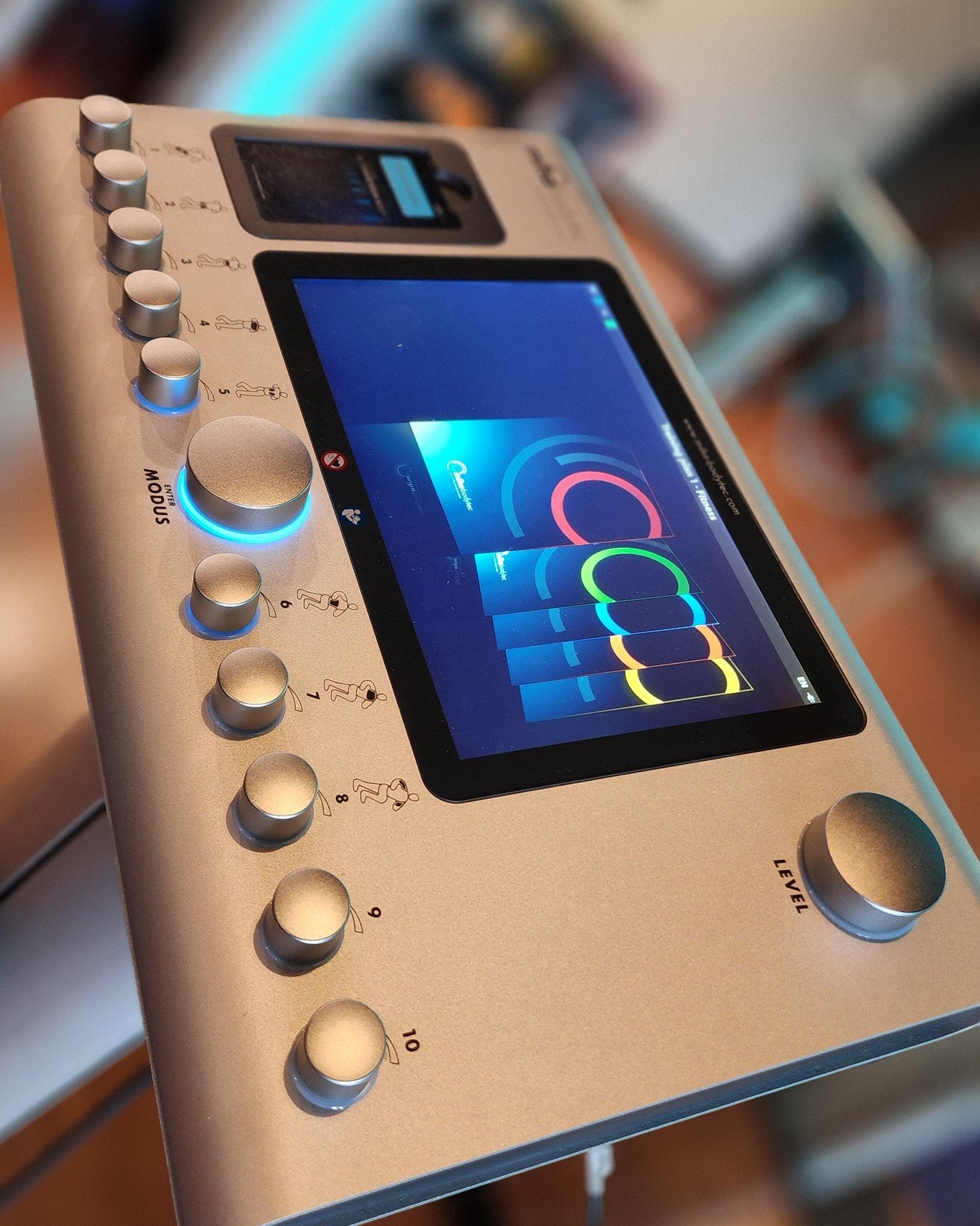 Close-up of a silver audio device with glowing blue and multicolor screens and many round knobs