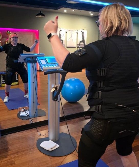 Woman exercising in a gym, using a cardio machine with a mirror and blue stability ball nearby