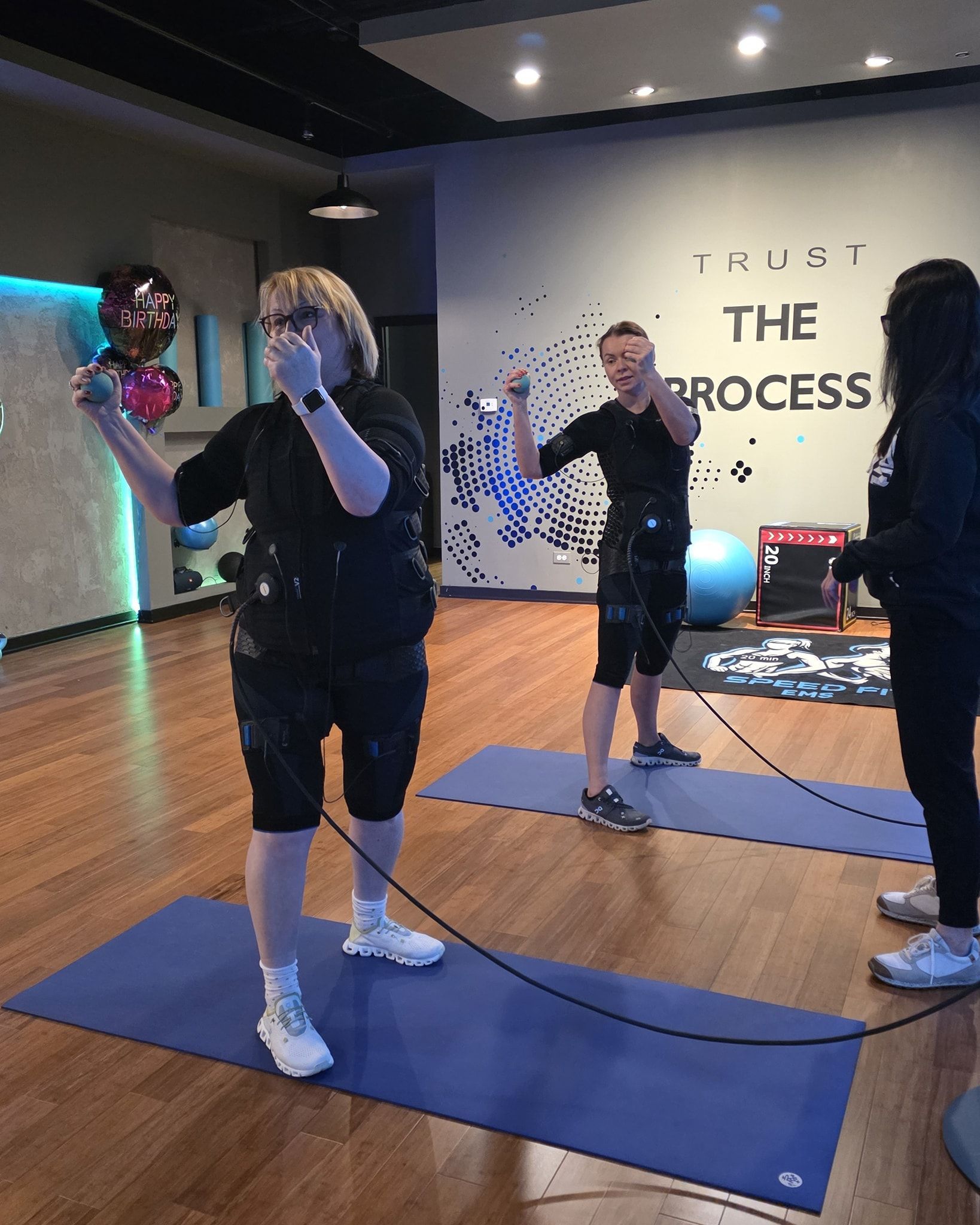 People exercising on blue mats in a studio with “THE PROCESS” on the wall