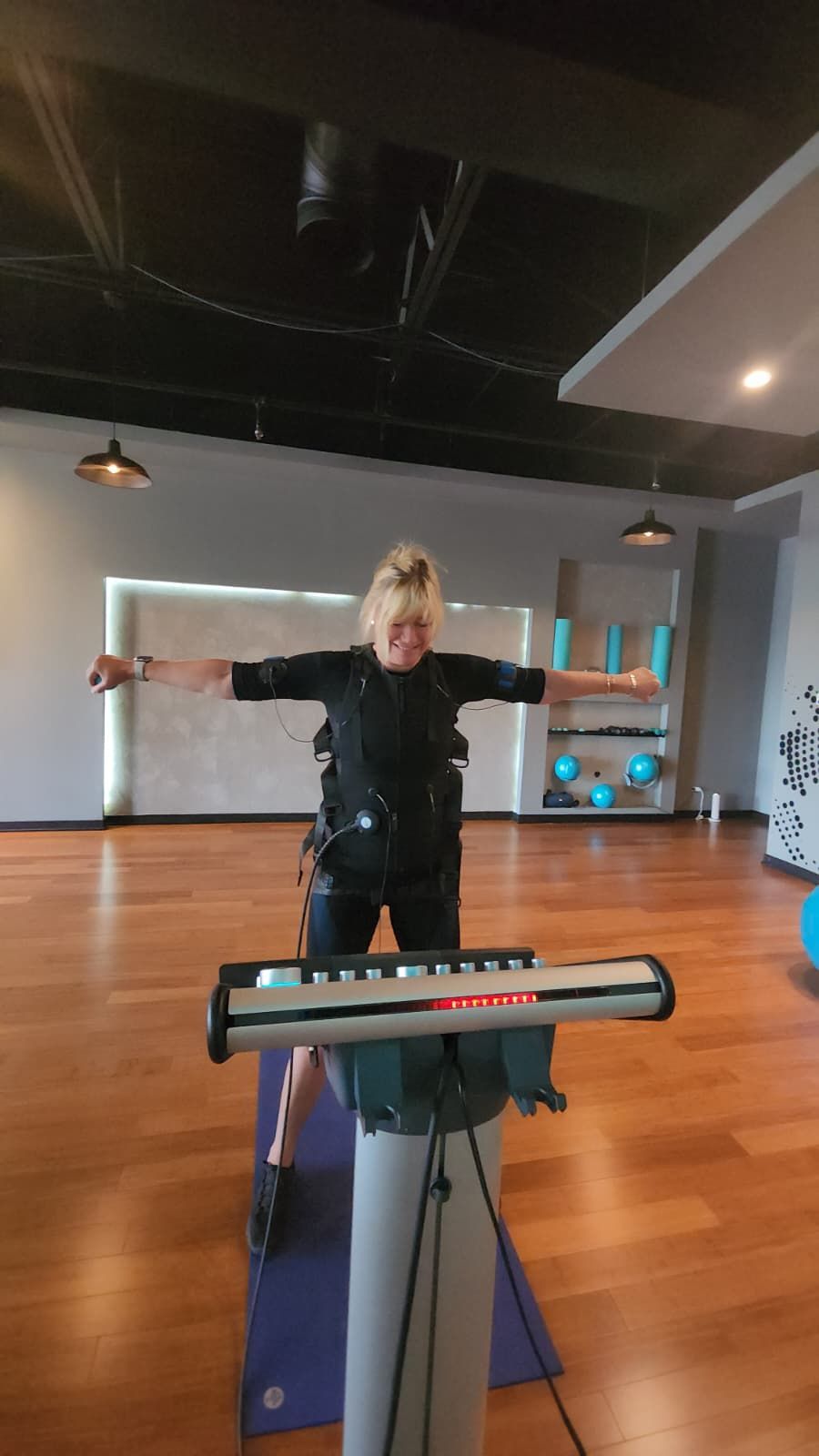 Person balancing with arms outstretched behind a keyboard in a dance studio with wood floors.