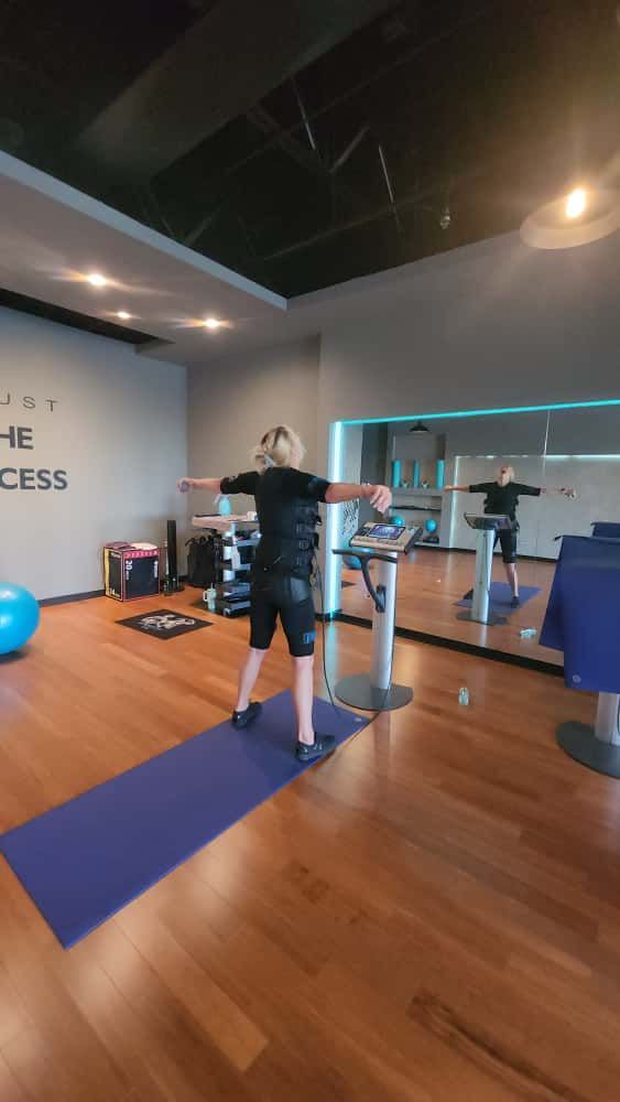 Person exercising on a gym machine in a modern studio with wood floors and mirrors
