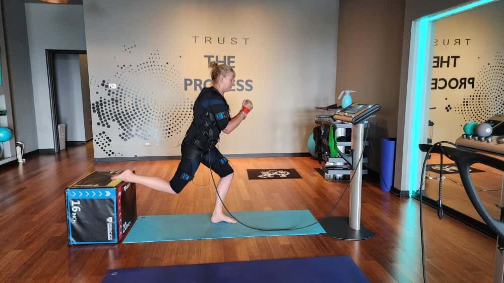 Person doing a yoga balance pose on a mat in a bright studio with mirrors and “TRUST THE PROCESS” on the wall
