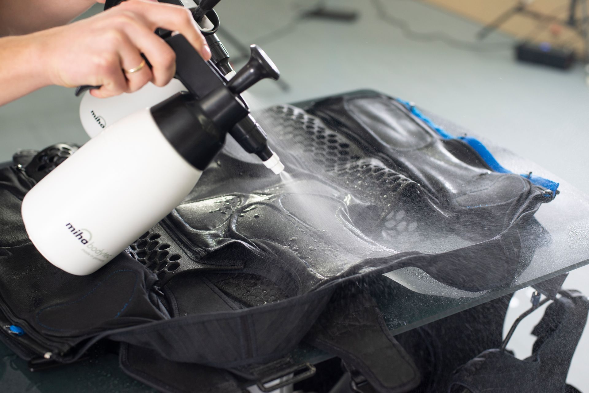 Hand spraying cleaner onto a black car interior surface with a foam bottle and glove in view