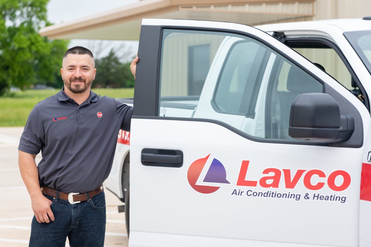 Man in gray shirt stands next to a white Lavco truck, smiling.