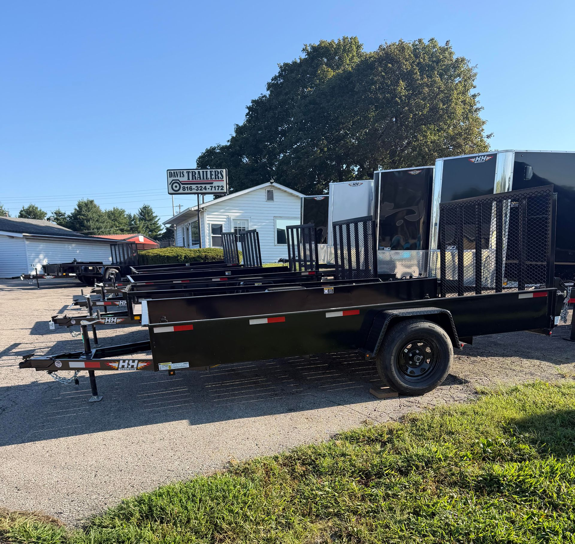 Black utility trailer with mesh side, parked outside a business.