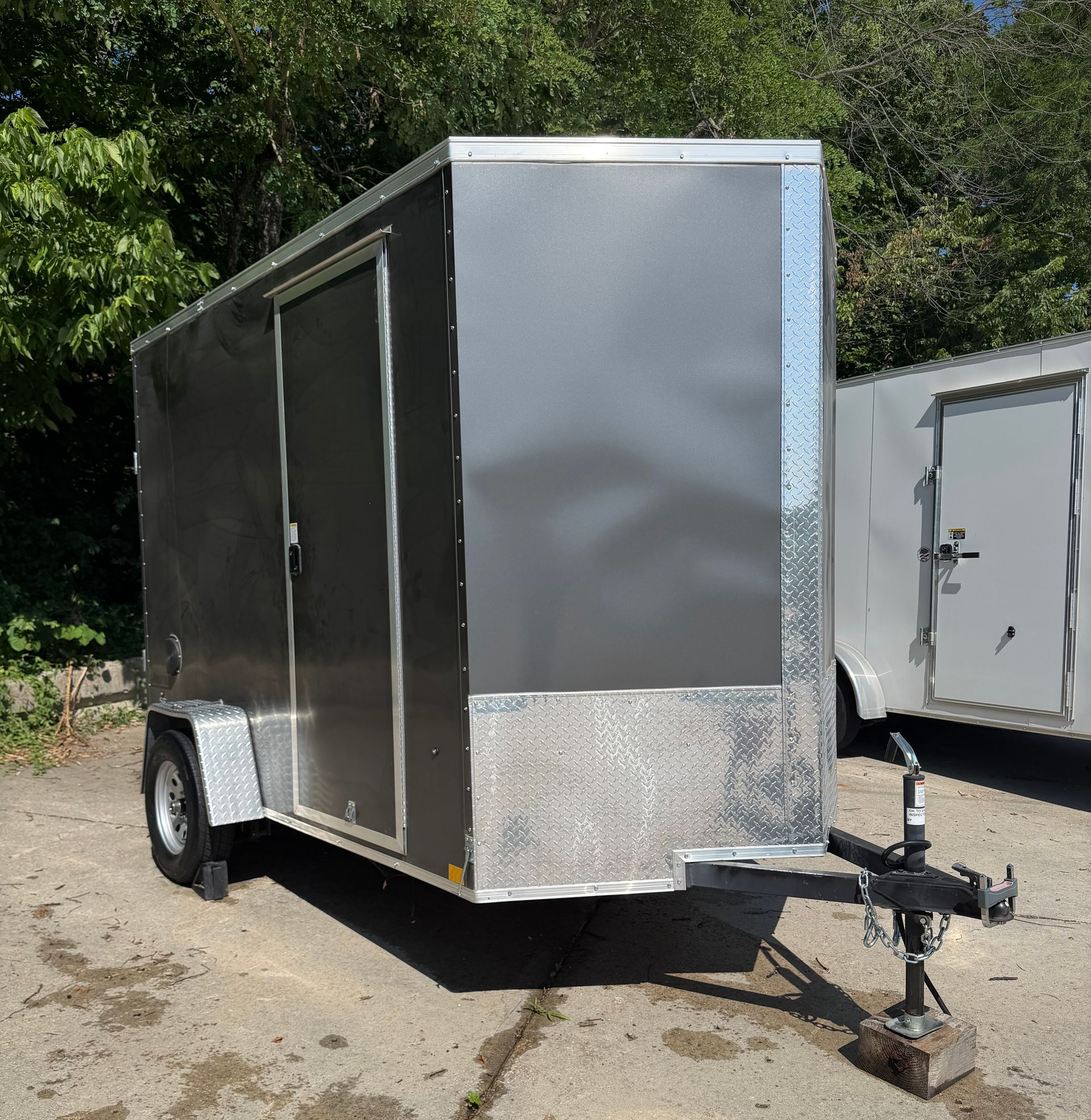 Black flatbed trailer with two axles parked on cracked pavement