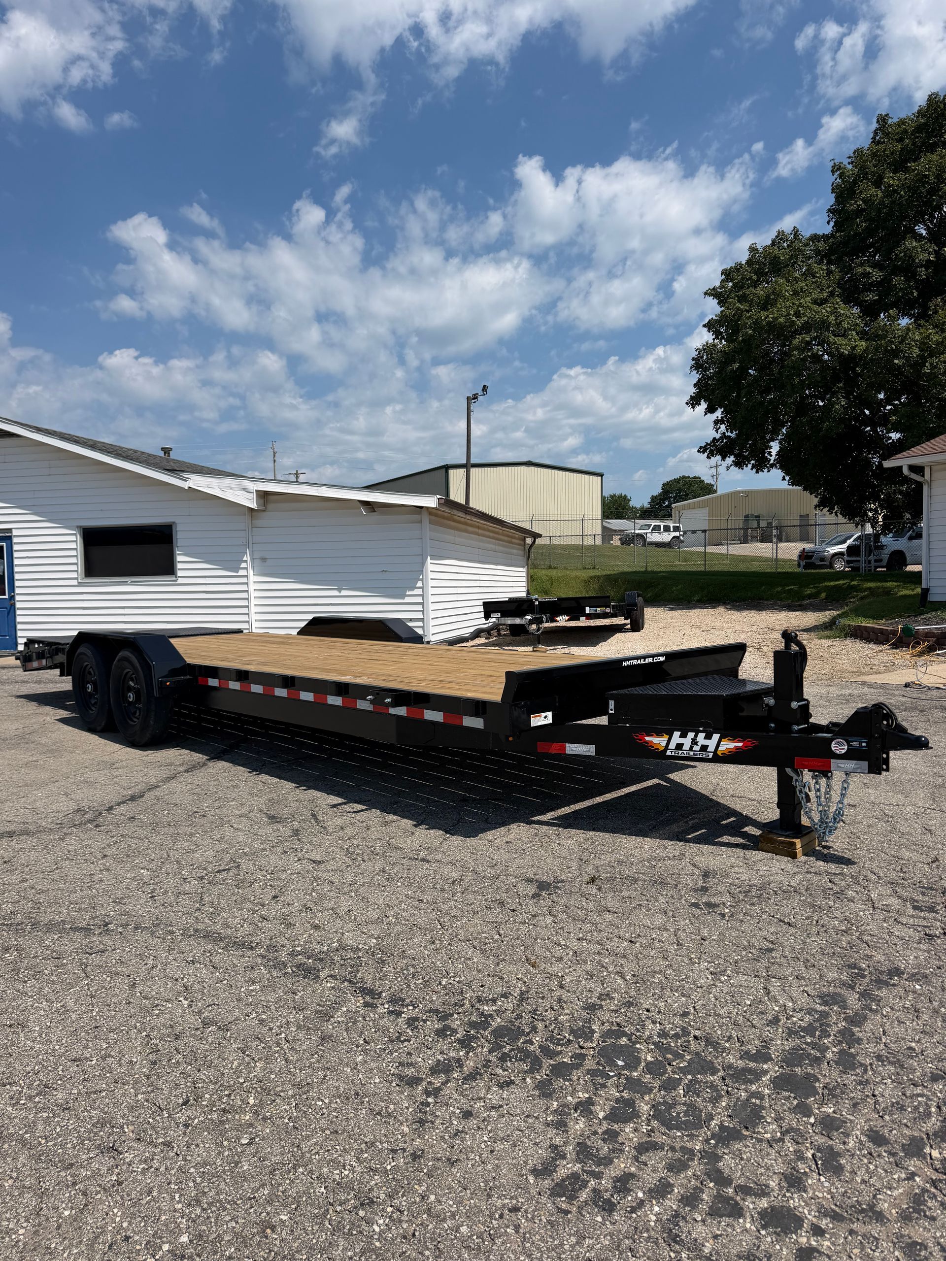 Black flatbed trailer parked on gravel