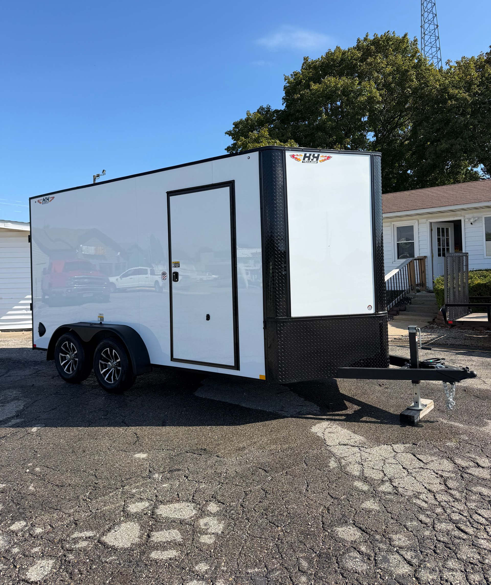 White enclosed cargo trailer with black wheels, door, and metal trim